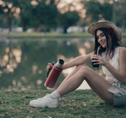 Young woman sitting by a lake drinking mate outdoors in Buenos Aires, Argentina.